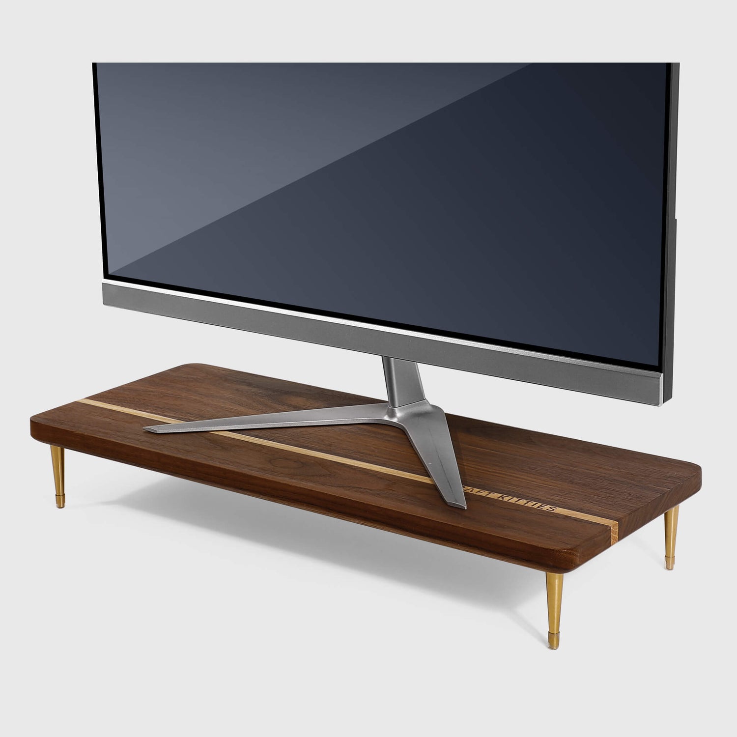 Home office with a walnut monitor stand at eye level, walnut vertical laptop stand, walnut cord organizer box, warm task lamp, and one small plant